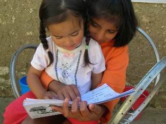 sopachuy.girls.reading 10-year old Lourdes (right) began her formal education this February and enjoys sharing what she is learning with others, like 2-year old Daniela. They both reside in Sopachuy.