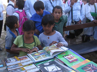 Kids surrounding the tables full of books to be donated to their new library.